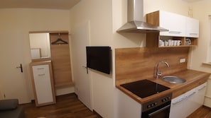 Compact kitchen with stove, sink, and wooden countertop.