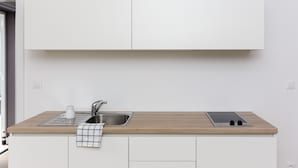 Una cocina moderna con armarios blancos, encimera de madera, un lavamanos y una estufa integrada.