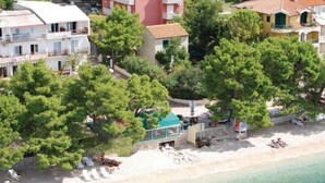 Um hotel à beira-mar com vários andares e uma pequena construção com telhado verde.
