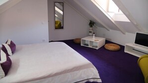 An attic bedroom with a bed, a TV, a mirror, and a window. - Apartments & Rooms Lejletul- Deluxe Studio Apartment (A2) (Dubrovnik)