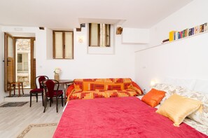 Une chambre avec un lit, un canapé, une table à manger avec des chaises et une bibliothèque.
