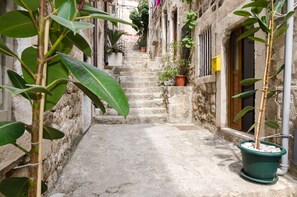 A narrow stone staircase leading up to a building with potted plants and a door.