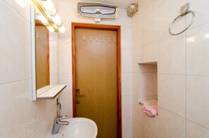 Une salle de bain avec une porte en bois, un miroir, un lavabo et un porte-serviettes.