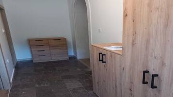 Een kamer met een houten garderobe, een klein bureau met papieren en een betegelde vloer.