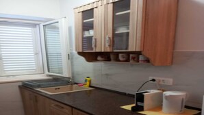 A kitchen with wooden cabinets, a sink, a countertop, and a window with blinds.