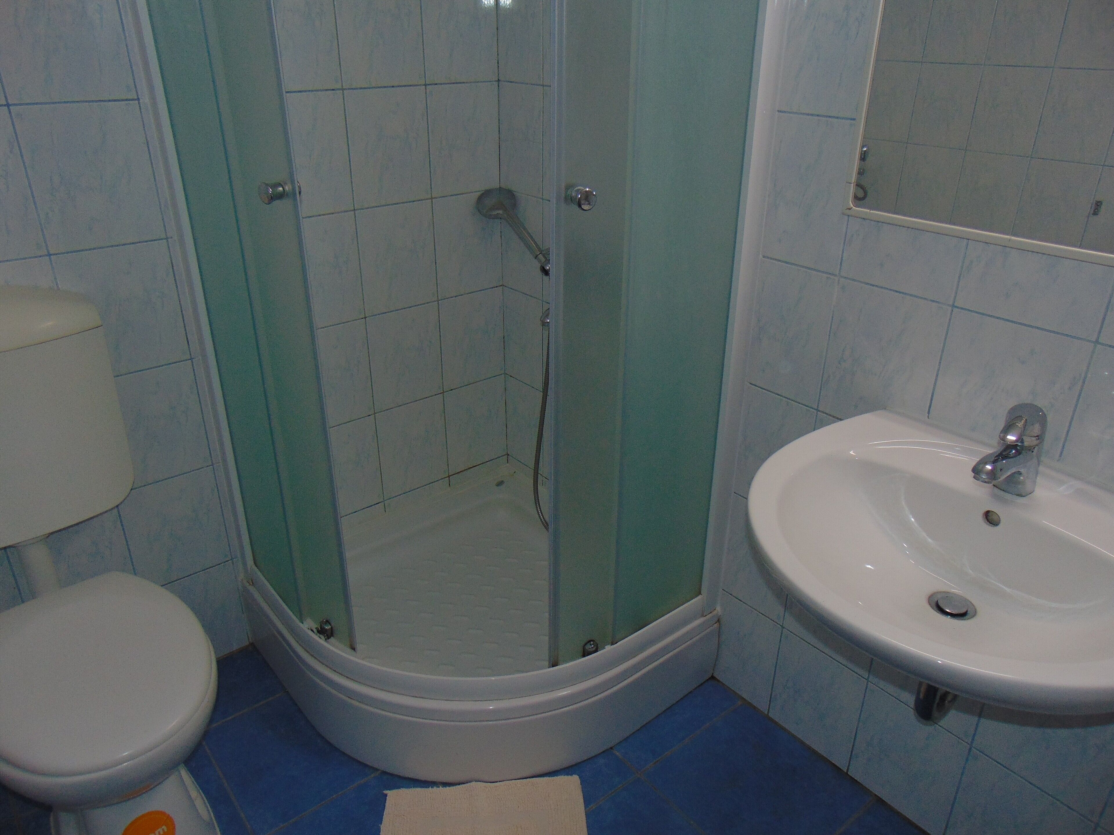 A bathroom with a shower, toilet, and sink.