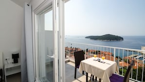 A balcony with a table set for two, overlooking a coastal view with a small island and a marina. - LUV Luxury Apartments - Studio Apartment with Balcony and Sea View (Dubrovnik)