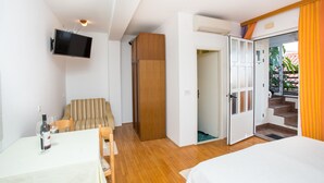 Ein Schlafzimmer mit Bett, einem an der Wand montierten Fernseher, einem Esstisch mit Stühlen und einer Holztür, die zu einer Treppe führt.