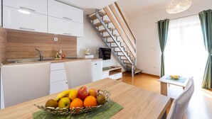 Una cocina moderna con armarios blancos, encimera de madera y una zona de comedor con una mesa para dos.