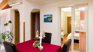 A dining area with a red tablecloth, white candelabra, and a painting on the wall. - Villa Bell Memories- Two Bedroom Apartment with Shared Terrace and Sea View (Cavtat)