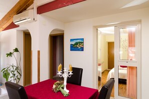 Un comedor con mantel rojo, candelabro blanco y un cuadro en la pared.