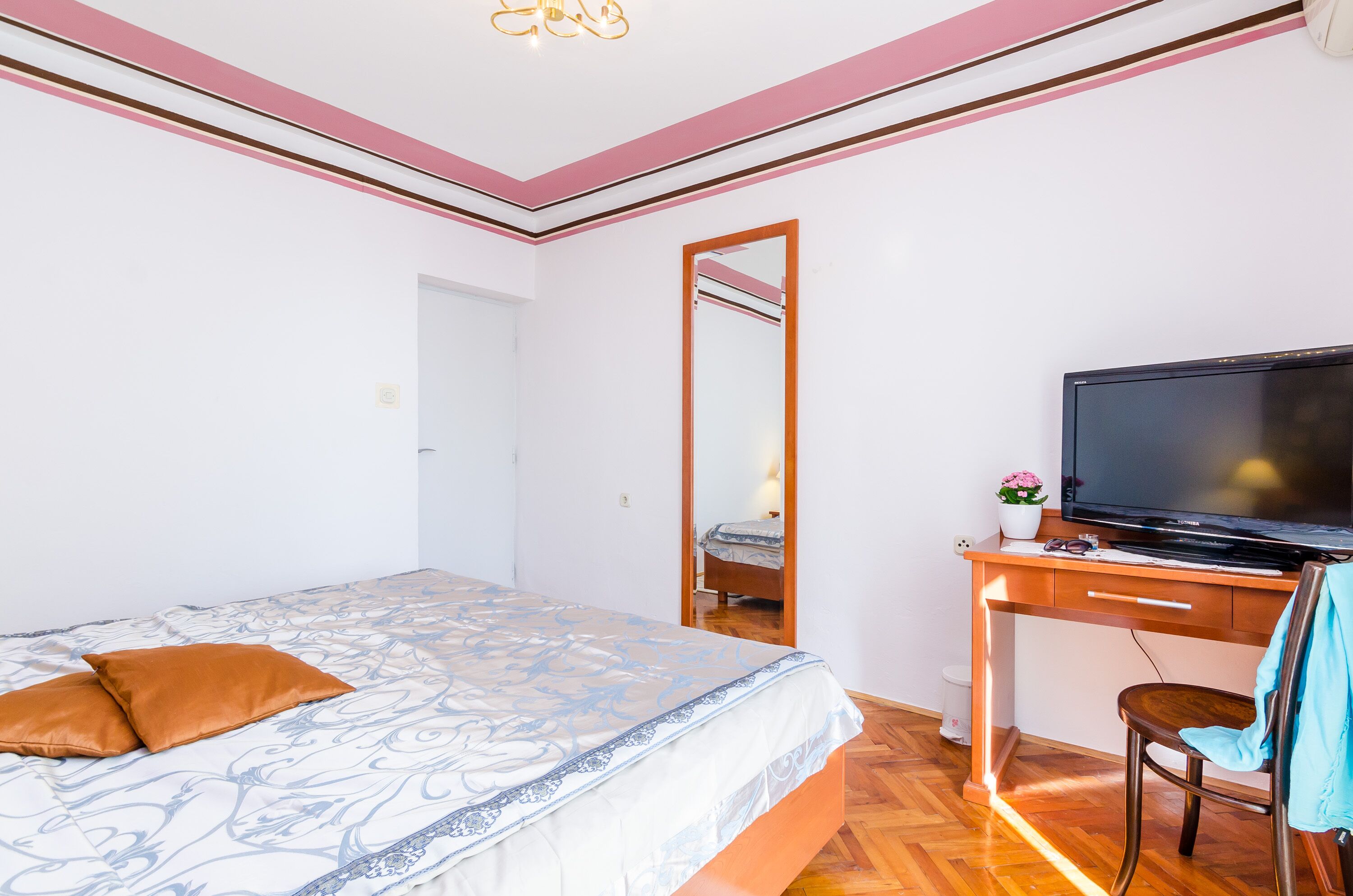 Ein Schlafzimmer mit Bett, Schreibtisch mit Fernseher, Spiegel und Stuhl.