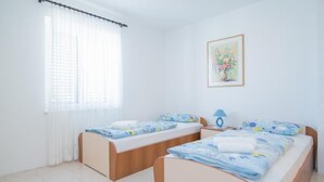 A room with two beds, a nightstand, a lamp, and a painting on the wall.