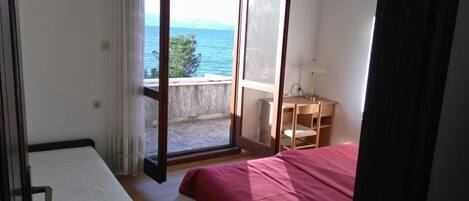 Un dormitorio con cama, escritorio y vista al mar.