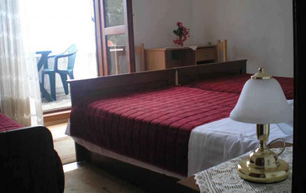 Una camera da letto con un letto singolo, un comodino con una lampada, una finestra e vista sull'esterno.