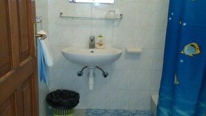 Une salle de bain avec un lavabo blanc, un miroir et un rideau de douche bleu orné de motifs de poissons.