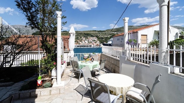 Eine Terrasse mit Tisch und Stühlen mit Blick auf eine Stadt mit traditioneller Architektur und blauem Himmel.