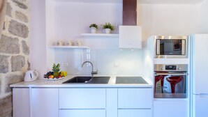 A modern kitchen with white cabinetry, a stainless steel sink, a built-in oven, and a microwave. - Apartments None & Nono-Comfort One-Bedroom Apartment with Shared Terrace (Cavtat)
