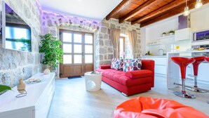 A modern living room with a stone wall, a red sofa, a white coffee table, and a red bean bag. - Apartments None & Nono-Comfort One-Bedroom Apartment with Shared Terrace (Cavtat)