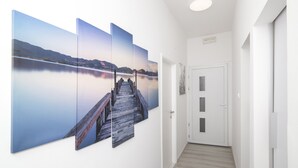 A hallway with a wooden floor, a white door, and a wall with a large landscape painting.