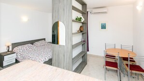 Un dormitorio con cama, mesita de noche, escritorio, silla, mesa y estantería.