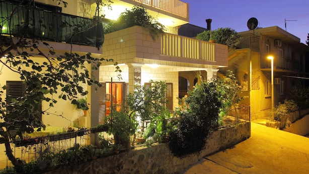 A two-story building with balconies, a stone wall, and potted plants. - Apartments Magda- Comfort Studio Apartment with Patio (Cavtat)