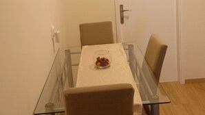 A dining area with a glass table, two chairs, a door, and a wall-mounted light switch. - Apartments Magda- Comfort Studio Apartment with Patio (Cavtat)