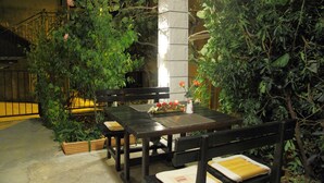 An outdoor dining area with wooden tables and benches, surrounded by lush greenery and flowering plants. - Apartments Magda- Comfort Studio Apartment with Patio (Cavtat)