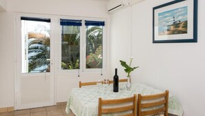 Un comedor con una mesa dispuesta para dos, una botella de vino y un jarrón con planta.