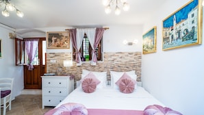 Une chambre à coucher comprenant un lit, une table de chevet, une chaise, une commode et une fenêtre avec des rideaux.