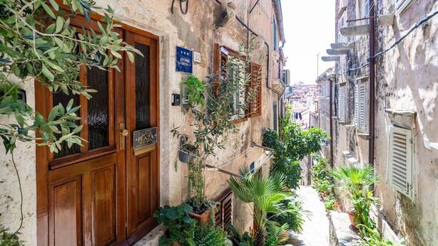 Une rue étroite avec une porte en bois et une enseigne indiquant qu’il s’agit d’un studio.