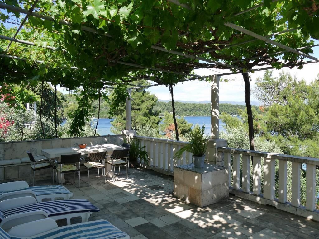 A terrace with a pergola, outdoor seating, and a view of the sea.
