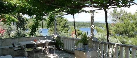 A terrace with a pergola, outdoor seating, and a view of the sea.