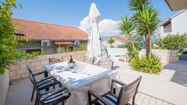 A patio with a table and chairs, surrounded by plants and a white umbrella. - Apartments Veve - One Bedroom Apartment with Terrace Sea View (Postira)