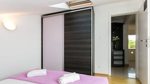 Ein modernes Schlafzimmer mit einem Bett, einer Schiebetür und Balkonblick.