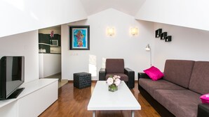Ein modernes Wohnzimmer mit einem weißen Couchtisch, einem braunen Sofa, einem Fernseher und einem Gemälde an der Wand.