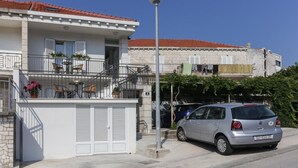 A two-story building with a balcony, outdoor seating, and a parked car. - Apartments Villa Providenca - Studio (Dubrovnik)