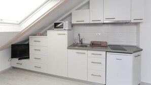 A compact kitchen with white cabinets, a built-in microwave, a sink, and a compact refrigerator. - Apartments Villa Providenca - Studio (Dubrovnik)