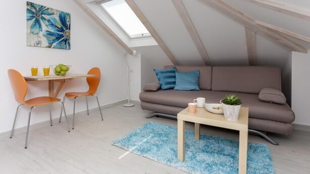 A cozy loft apartment with a dining area, a sofa, and a skylight. - Apartments Villa Providenca - Studio (Dubrovnik)