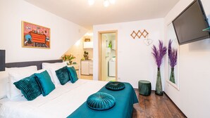 Ett hotellrum med en säng, en tv som är monterad på väggen och en dörr som leder till ett badrum.
