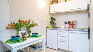 Ett kök med vita skåp, en diskho och ett bord med en grön bordsduk. På bordet står en bukett orange tulpaner och en vas med blommor.