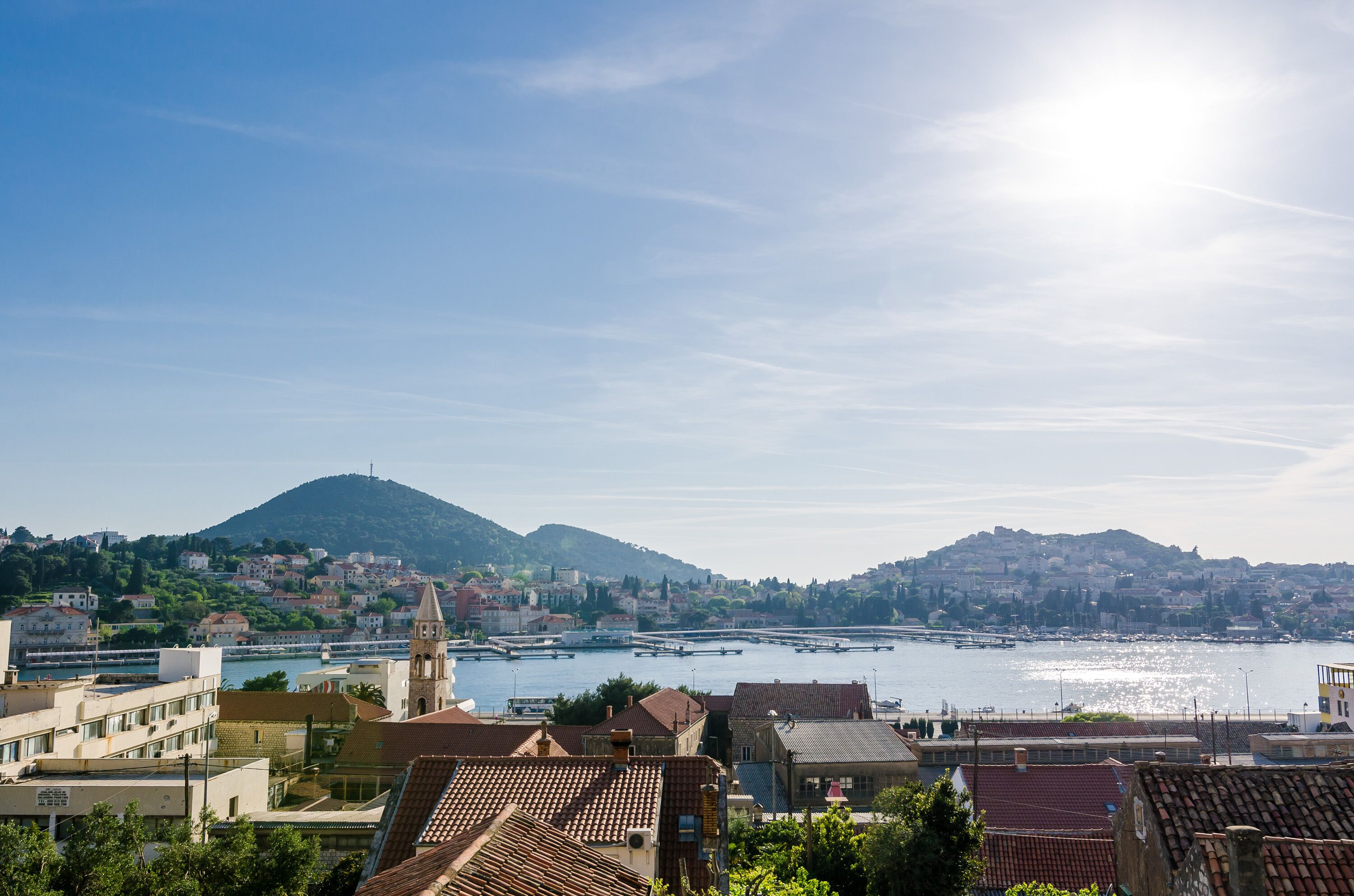 A coastal town with buildings, a church, and a hill in the background.