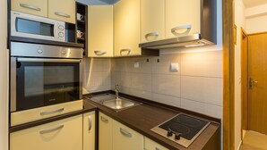 A compact kitchen with a built-in microwave, oven, and stovetop.