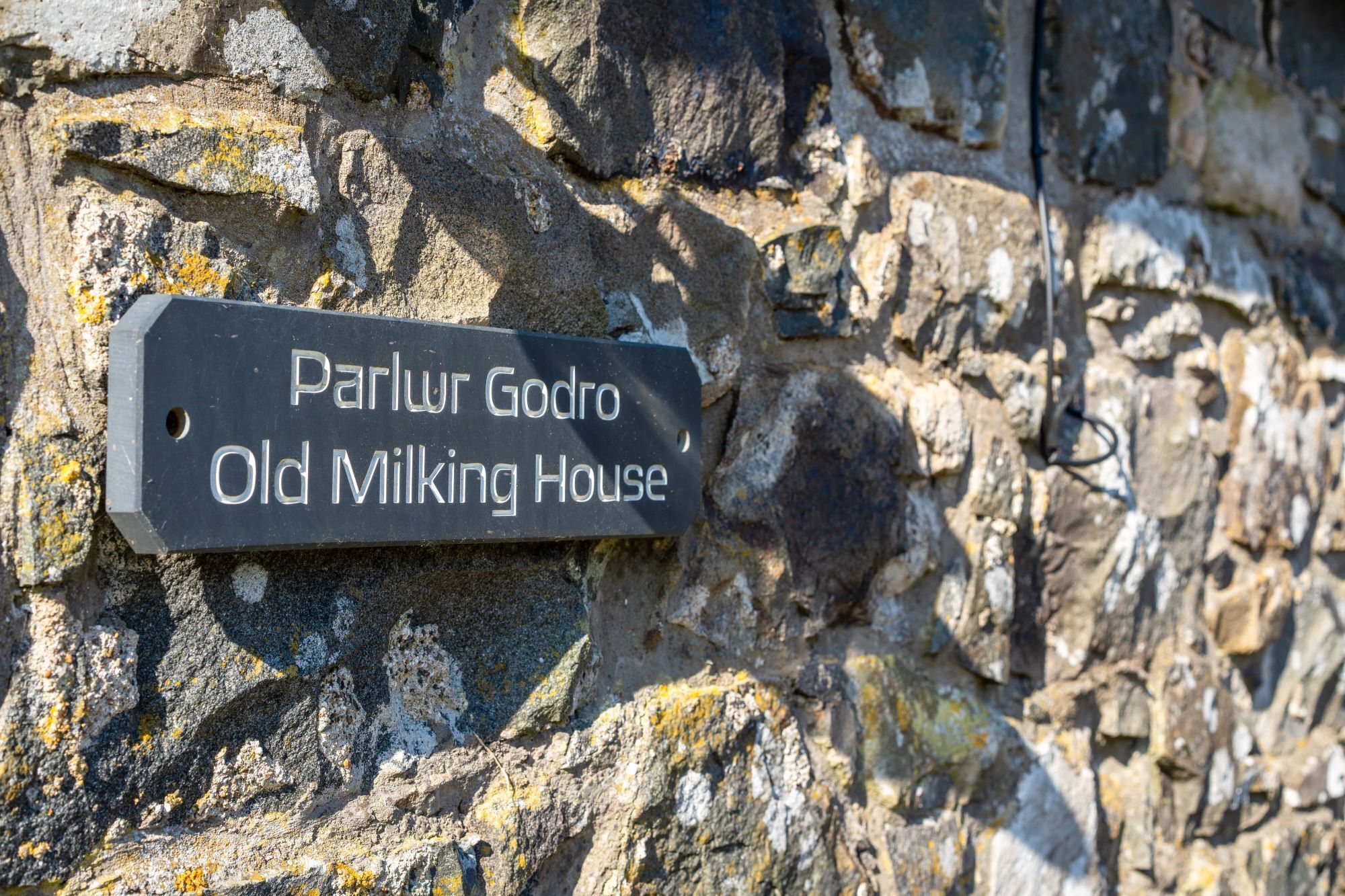 Um aviso numa parede de pedra com a inscrição 'Parlur Godro Old Milking House'.
