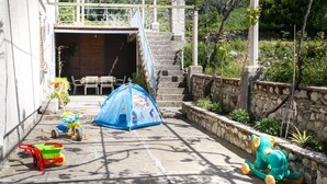 A courtyard with a blue tent, a green and red toy car, a yellow tricycle, and a green bear sculpture. - Apartment Marko - Three-Bedroom Apartment with Terrace and Sea View (Brsečine) (Brsecine)