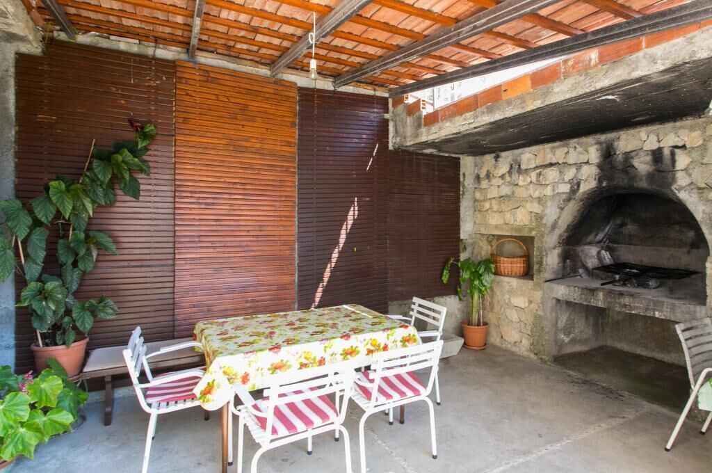 An outdoor patio with a stone oven, wooden slatted walls, and potted plants.