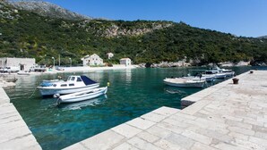 A marina with boats docked, a stone pier, and buildings on a hillside. - Apartment Marko - Three-Bedroom Apartment with Terrace and Sea View (Brsečine) (Brsecine)