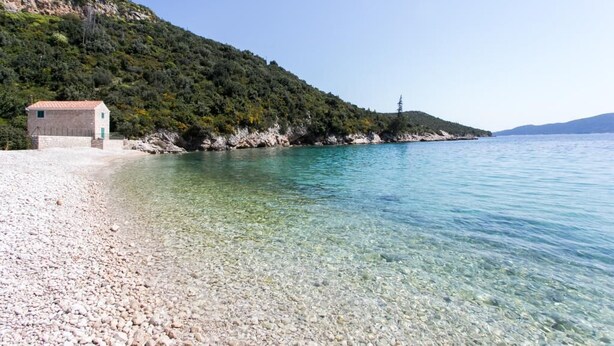 A pebble beach with clear water and a small building on a hillside. - Apartment Marko - Three-Bedroom Apartment with Terrace and Sea View (Brsečine) (Brsecine)