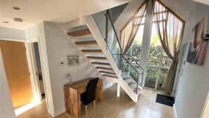 Un intérieur moderne avec un escalier, un bureau et une grande fenêtre avec des rideaux.