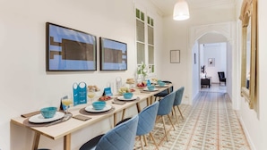Een eethoek met een lange tafel, blauwe stoelen en een vloer met patroon.